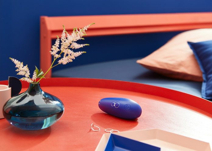 Photo by Womanizer Toys brown and white flowers in blue ceramic vase on brown wooden table